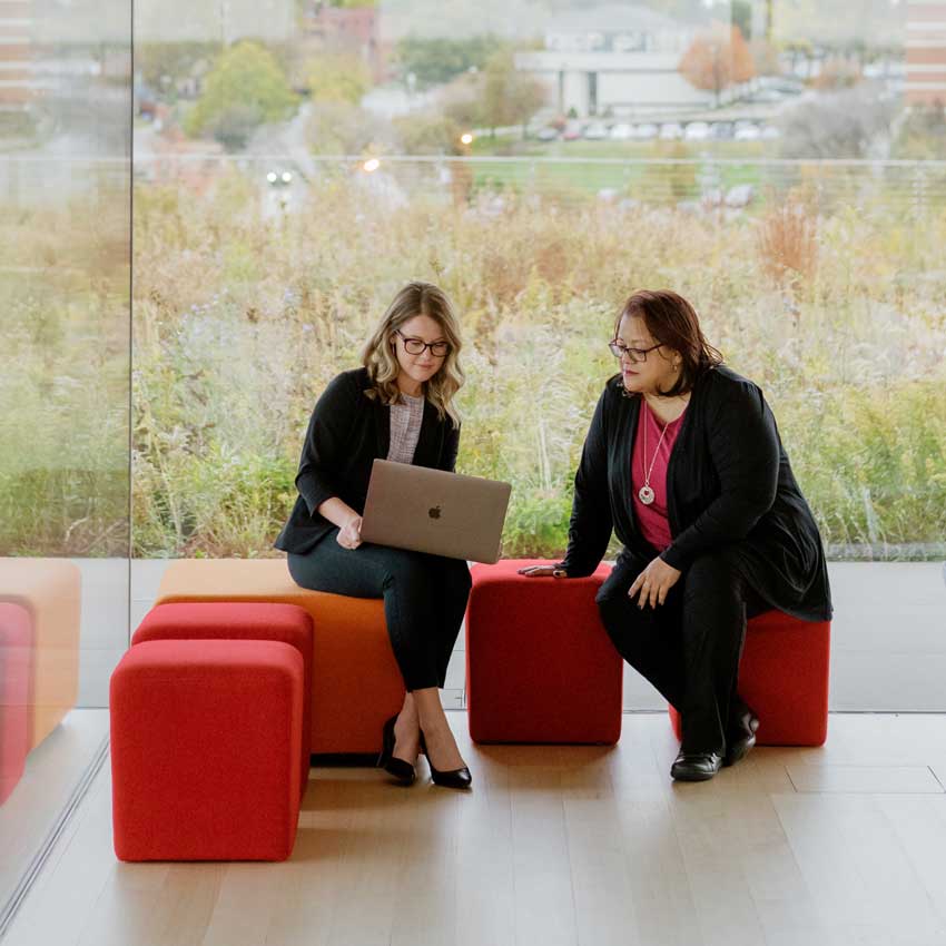 two individuals sitting with laptops