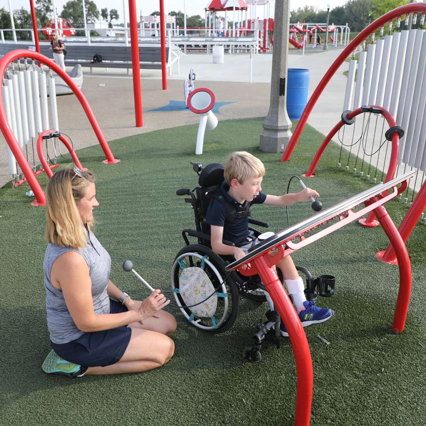 a child in a wheelchair plays while an adult looks on