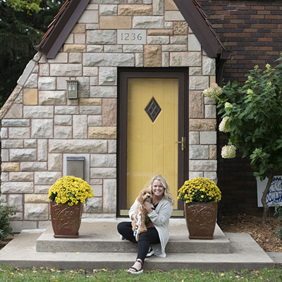 a woman and her dog in front of an a-frame house