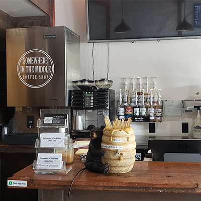 The inside of a coffee shop with the wall lined with syrups.
