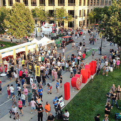 overhead view of a crowd on a street with several vendors set up on the side.