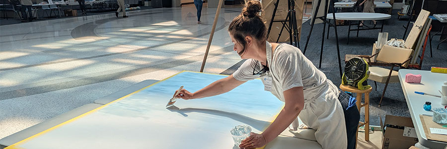 A woman painting on a large piece of paper