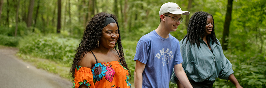 Three young adults walking on a trail