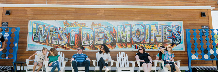 A group of people sitting in front of a West Des Moines mural