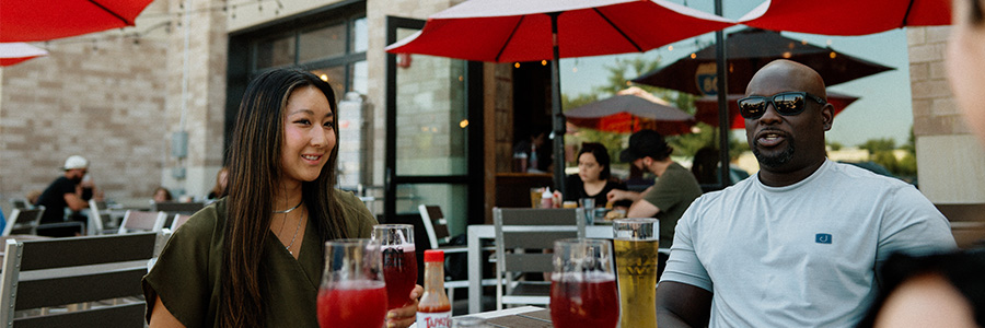 Two people sitting at a table with drinks while talking
