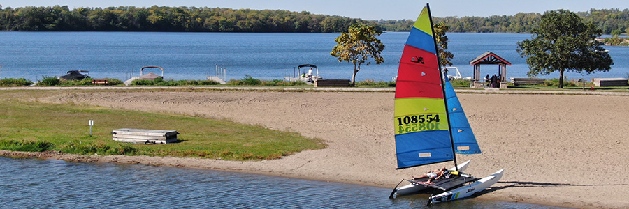 A boat on the sand with a man tanning on it.