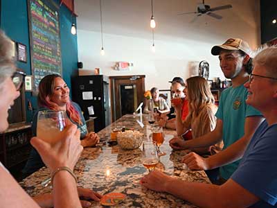 a bar top with a group of people gatherered around it smiling and enjoying drinks