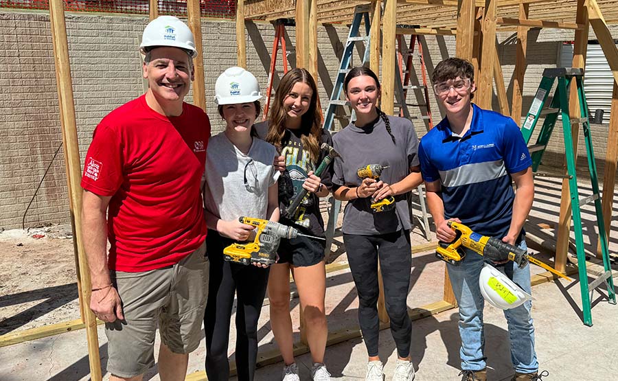 A group of five people holding tools and standing next 