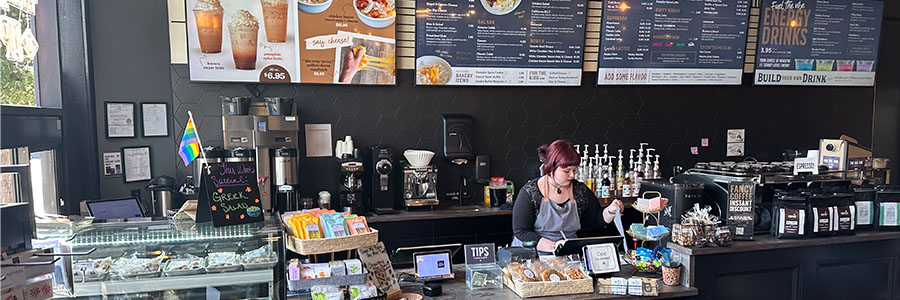 A woman behind a counter, making coffee drinks.