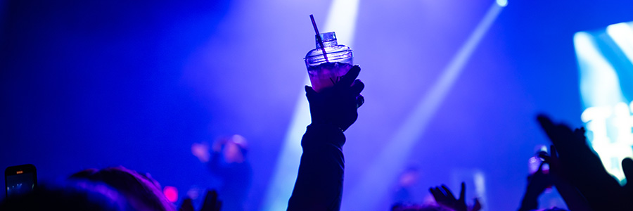 A person holding up a drink in a dark room lit by strobe lights