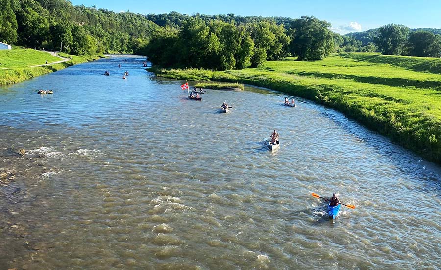 A group of kayaks going down the river surrounded by gr