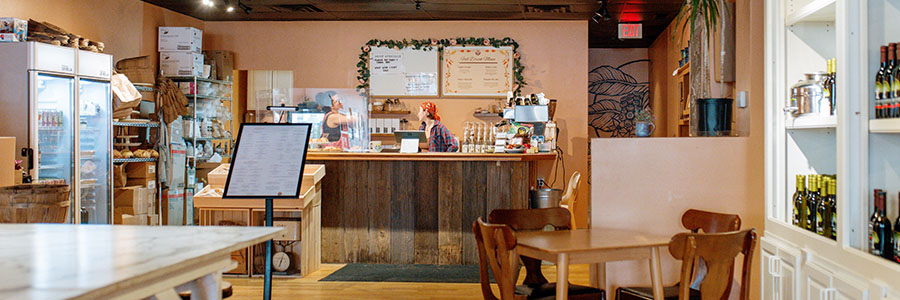 Inside Savor the Rise there are pink walls, several tables for guests and olive oil displayed on the wall.