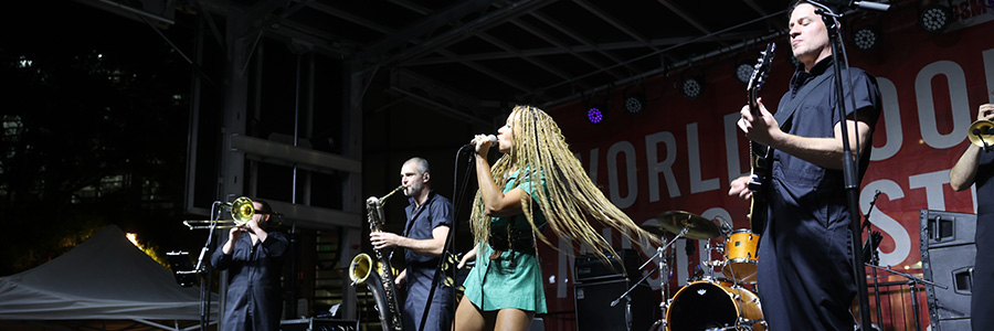 World Food and Music Festival A band on stage performing. The singer is swinging her hair around.