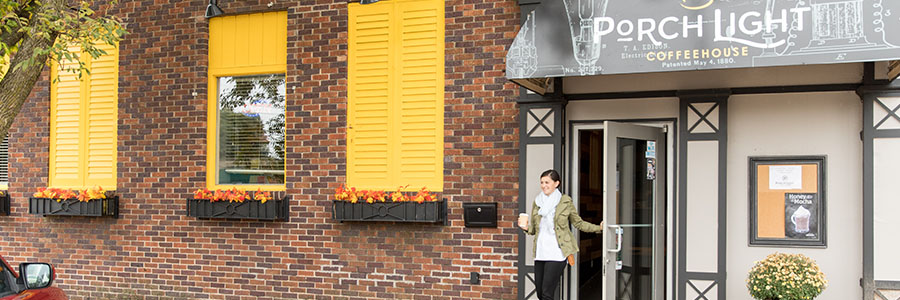 Porchlight Coffeehouse A person walking out of a coffee shop with fall decorations on the exterior.