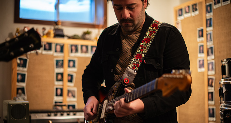 A man standing and playing the guitar