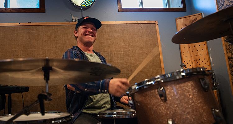 Chris Hansen A man playing the drums and smiling.