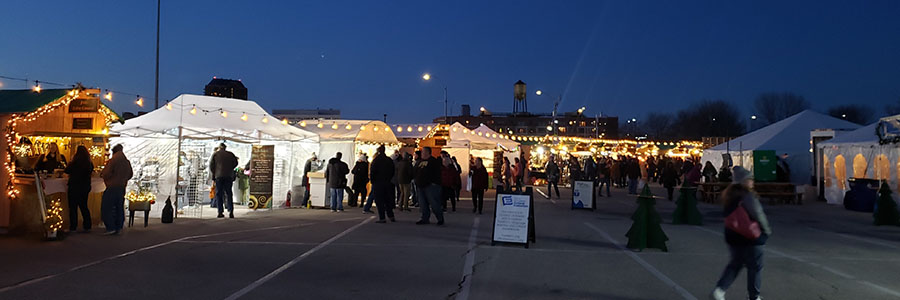 Several tents lit up outside and people gathering around them to shop.