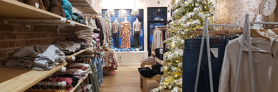 The inside of a shop with clothes and a Christmas tree