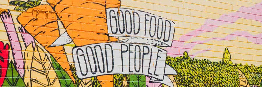 A mural with carrots and fields. There is a painted banner that says "good food, good people."