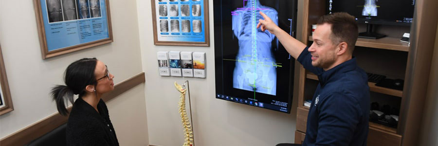 a chiropractor showing a woman an x-ray and pointing to the neck