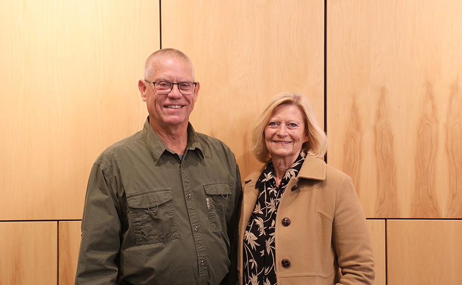 A couple smiling in front of a blank wall