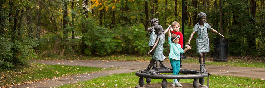 two children holding hands with statues